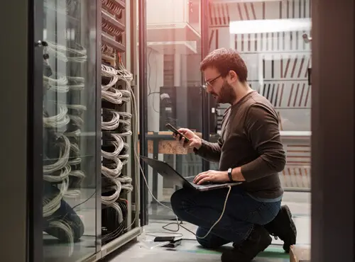 En person kontrollerar tekniken i ett ljudisolerat serverrum.