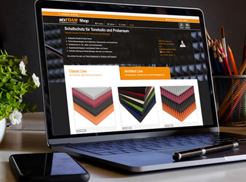 En laptop visar aixFOAM-online-butiken med ljudabsorbenter och bullerskyddsprodukter.