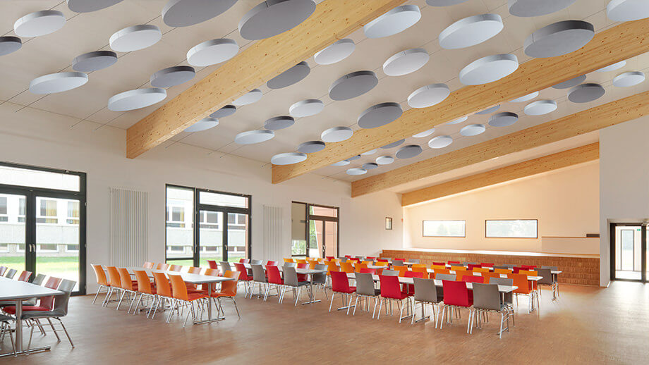 Round acoustic ceiling sails in a cafeteria improve the acoustics.